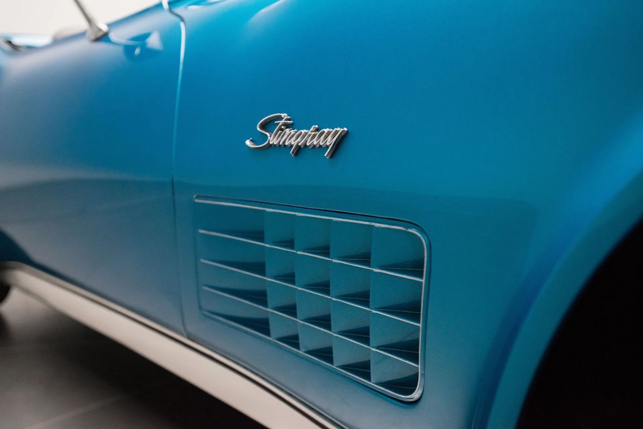 ChatGPT said:  On the 1970 Corvette, Chevrolet refined the exterior side-vent design into the bold, square-patterned louver seen here—an evolution that gave the Stingray’s fenders a more aggressive and technical appearance. Replacing the vertical vents used from 1968–69, this crisp, grid-style insert became a defining detail of the 1970 model year, reflecting the brand’s growing emphasis on precision and performance styling. Paired with the elegant Stingray script emblem, this subtle but striking change helped mark the dawn of a new decade for America’s sports car—one that balanced sculpted beauty with mechanical purpose. (Image courtesy of RK Motors)