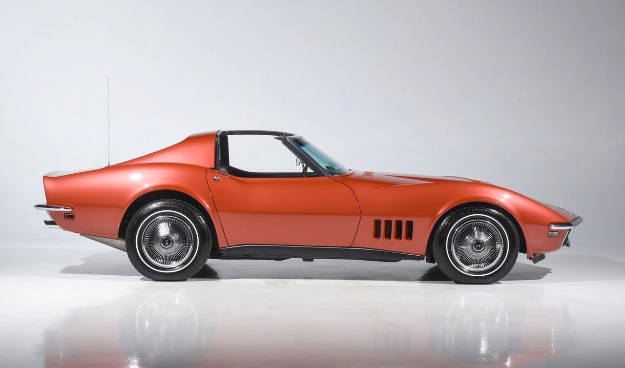 The 1968 Corvette traded the C2’s crisp Sting Ray lines for a full “shark” profile—long, needle-nose hood, separate muscular fender peaks, and a pinched waist that reads like sculpture in side view. The coupe’s new modular roof (T-tops with a removable rear window) replaced the C2’s fixed fastback, while vent wings disappeared in favor of Astro Ventilation for a cleaner glass-to-body look. A vacuum door hides the wipers for a smooth cowl—another departure from the C2’s exposed hardware—and the front fender gills become four vertical slots rather than the Sting Ray’s horizontal trim. Wheel openings are round and generous, the tail is more tapered, and the whole car grows in overall length while retaining the 98-inch wheelbase. Even with chrome bumpers still in place for ’68, the message is clear: this is the beginning of the shark era, not a continuation of the Sting Ray. (Image courtesy of motorcarclassics.com)