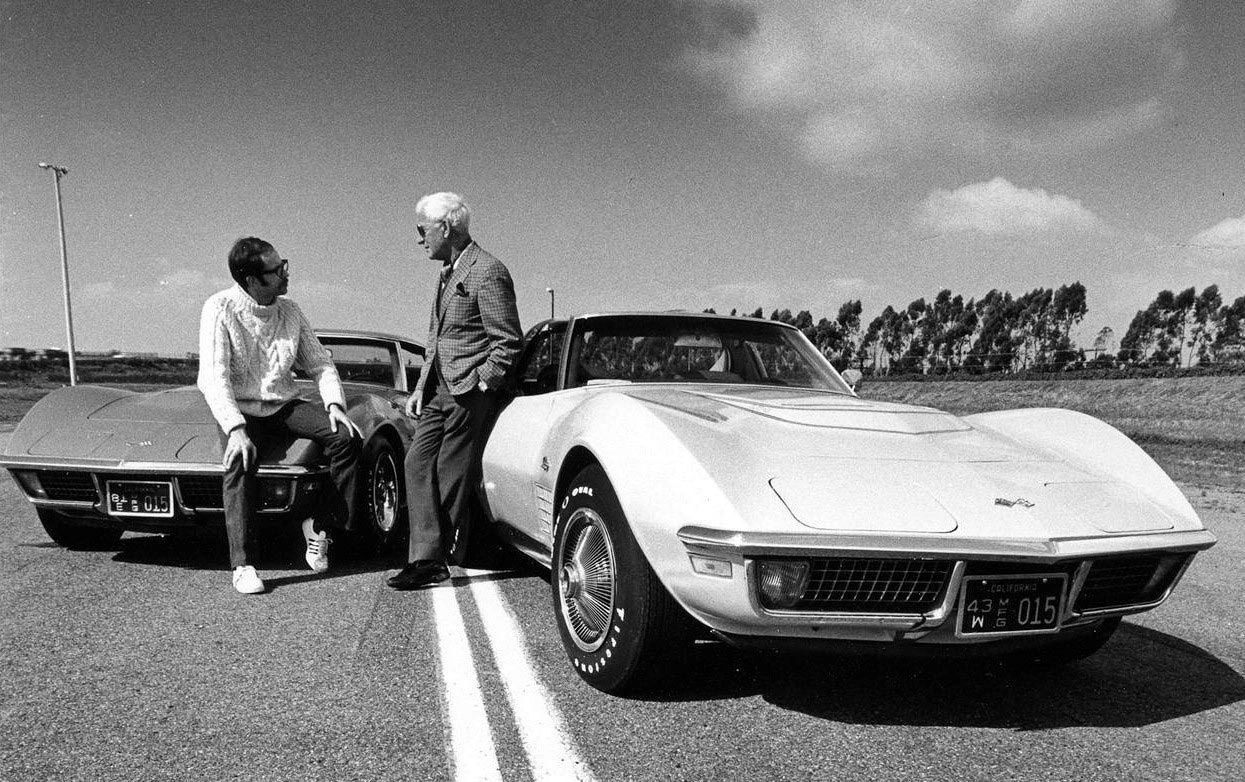 Zora Arkus-Duntov—Corvette’s legendary chief engineer and so-called “Father of the Corvette”—stands at center stage in this early-1970s scene, chatting with a young enthusiast or journalist while a pair of chrome-bumper C3 Stingrays frame the conversation. The cars wear California manufacturer plates, a reminder that Chevrolet often brought pre-production or press Corvettes west to evaluate them on local roads and tracks and to court the media with ride-and-drive events. Duntov, with his trademark white hair and tailored jacket, looks every bit the European racing engineer who had pushed America’s sports car toward genuine world-class performance—from fuel-injected small-blocks in the late ’50s to the fire-breathing LT-1 and big-block 454s that powered these “Shark” era cars. It’s a quiet moment, but historically rich: the man who turned the Corvette into a serious performance icon, standing casually in the lane with the very machines that carried his philosophy of speed and handling into a new decade. (Image courtesy of GM Media LLC)