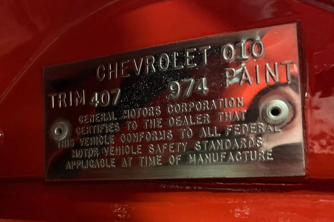 This identification tag is from a 1969 Chevrolet Corvette, showing Trim Code 407, which indicates a red vinyl interior, and Paint Code 974, designating Monza Red. Together, these codes confirm that the car originally left the factory in a striking Monza Red exterior paired with a red vinyl cabin. The tag also carries the standard GM certification language, verifying that the vehicle met all federal safety standards at the time of manufacture. (Image courtesy of RK Motors)