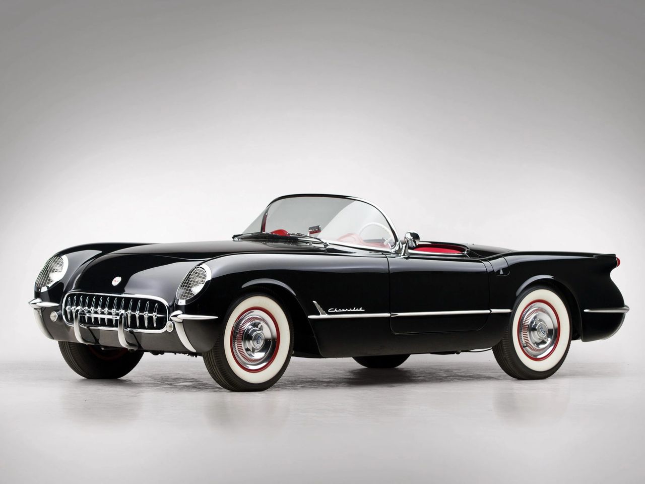 This sleek 1954 Chevrolet Corvette in rare Onyx Black shows just how far “America’s Sports Car” had come in only its second year. Unlike the Polo White–only 1953s, Chevrolet expanded the Corvette’s palette in ’54, making this black-on-red combination one of the most striking of the early cars. Beneath the hood remained the familiar 235ci Blue Flame six with triple Carter carbs, paired to the Powerglide automatic — but subtle refinements, from re-routed exhaust outlets to upgraded wiring, made the car more livable. Today, examples like this stand as elegant reminders of Corvette’s formative years, when Chevrolet was still convincing the public that an American sports car truly belonged on the road.