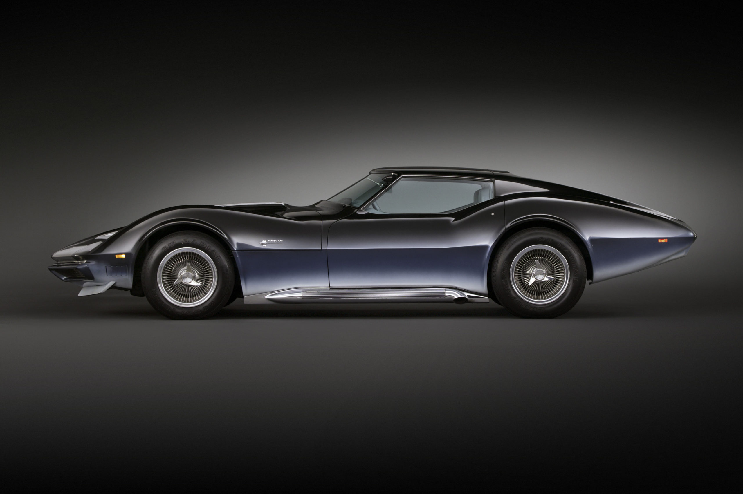 The 1969 Chevrolet Corvette Manta Ray concept, finished in a deep blue-to-black gradient. Its exaggerated fender arches, long tapering tail, turbine-style wheels, and low, flowing roofline emphasize the experimental aerodynamics and futuristic design language that helped shape the C3 Corvette era.