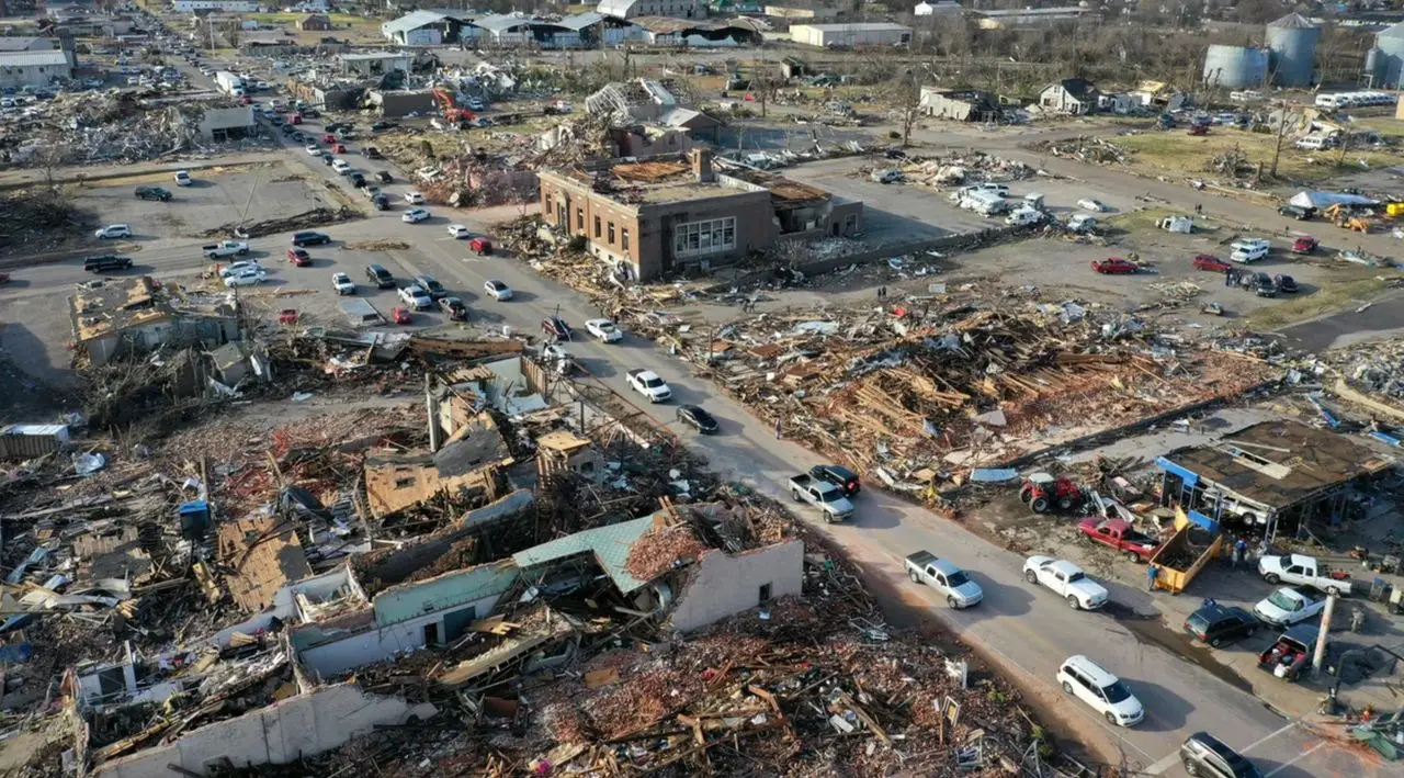 The scene in Mayfield, Kentucky after the December 11, 2021 tornado outbreak shows entire blocks leveled, historic buildings gutted, and neighborhoods reduced to splinters. The long-track, late-season storm became one of the deadliest and most destructive in Kentucky’s history, leaving dozens dead and thousands displaced across the western part of the state. In Mayfield, the courthouse district and downtown corridor suffered catastrophic damage as first responders and volunteers began days of search, rescue, and recovery. This image captures the scale of loss that would frame a long rebuild. (Image courtesy of the Atlantic)