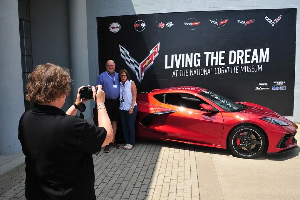 The R8C Museum Delivery turned a Corvette handoff into a curated experience at the National Corvette Museum: owners were welcomed with signage, a VIP tour, and their car staged on Corvette Boulevard before a delivery host led a full orientation and formal presentation. Each R8C car received a door-jamb decal, a personalized dash and wall plaque, a one-year family museum membership, professional photos, and many buyers capped the day with lead/follow laps at NCM Motorsports Park. The program hit a milestone in 2021 when, on July 2, the museum celebrated its 14,000th R8C delivery—a Red Mist Stingray coupe handed to first-time Corvette owners John and Gina Engel of Omaha, Nebraska. (Image courtesy of the National Corvette Museum)