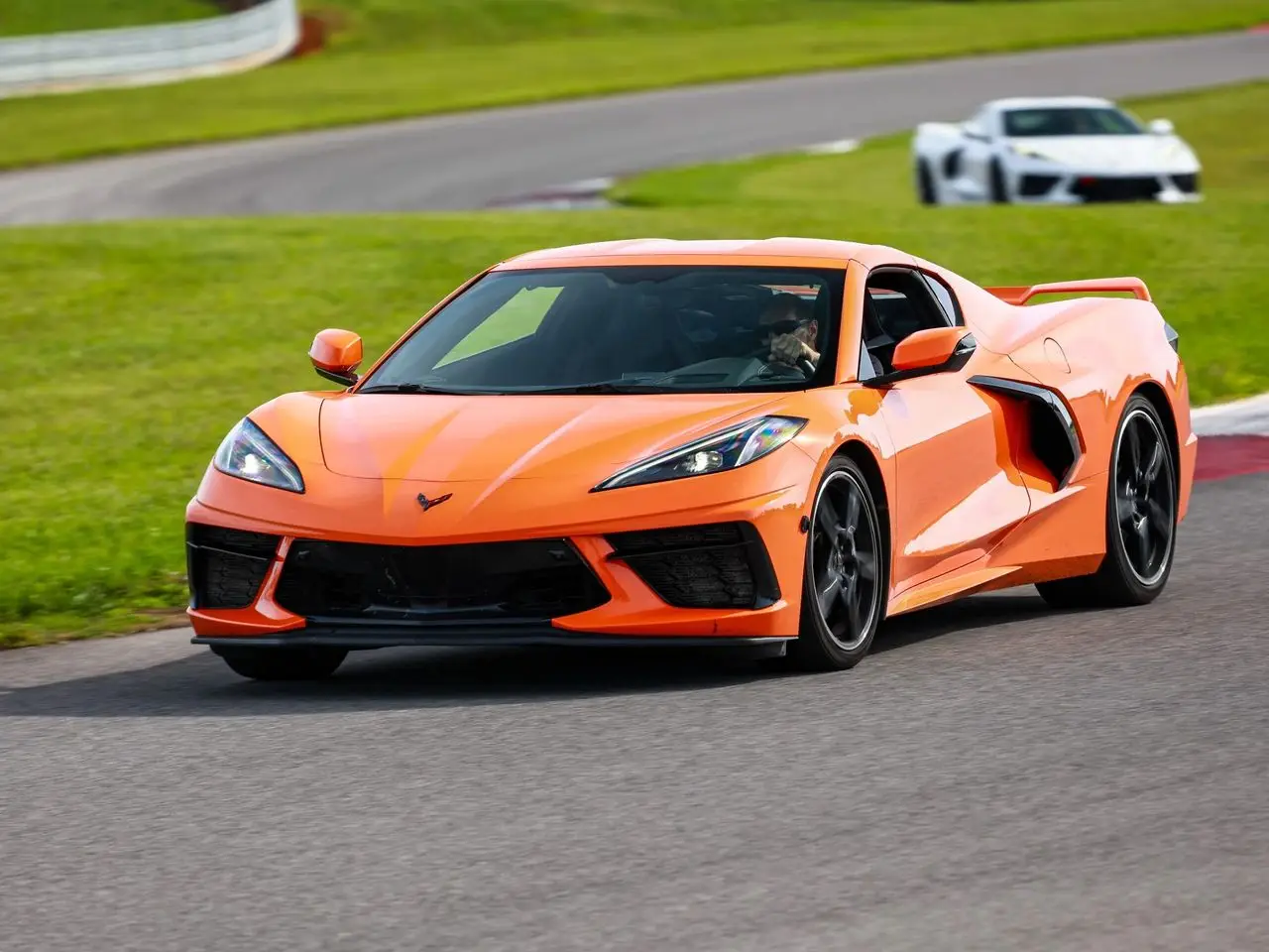Shot at NCM Motorsports Park—the 3.2-mile road course across from the National Corvette Museum in Bowling Green—this Sebring Orange Tintcoat Stingray underscores why the 2021 car’s numbers mattered on real pavement. With Z51 hardware, the mid-engine C8 routinely posted 0–60 in 2.8–2.9 sec and 11.1–11.2 sec quarters at 122–123 mph, and turned a 2:49.0 Lightning Lap at VIR—performance rooted in the LT2 + TR-9080 DCT combo, eLSD, Michelin PS4S tires, and FE4 Magnetic Ride Control calibration. The track is a stone’s throw from the assembly plant, making it a natural proving ground where the 2021’s updates—clearer Track tach/drive-mode visuals and the fine-tuned chassis—translated directly into confident laps. (Image courtesy of NCM Motorsports Park)