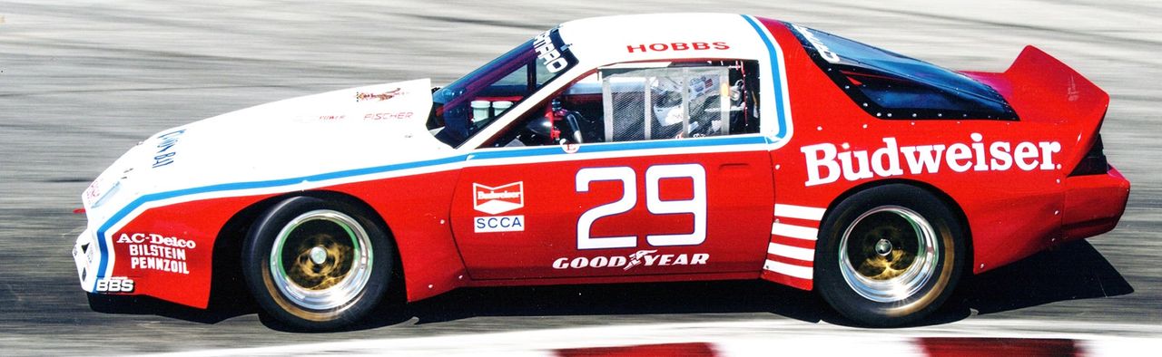 Budweiser red, #29, and pure Trans-Am thunder—the DeAtley Camaro put big-bore brutality in a wind-tunnel suit. A tube-frame rocket with small-block V8, BBS wheels, and side-exit bark, it carried David Hobbs to front-row pace and crowd-pleasing slides. Northwest-backed, nationally feared: a quintessential ’80s Camaro racer.