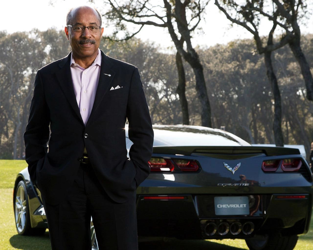 Ed Welburn, the former General Motors' Vice President of Global Design, stands beside the seventh-gen Corvette, the quad-center exhaust and crisp rear graphic telegraphing purpose. The pairing captures the era’s mantra—taut surfacing, integrated aero, and a stance that looks fast standing still. It’s a portrait of the stewardship that pushed Corvette toward world-class fit, finish, and feel.