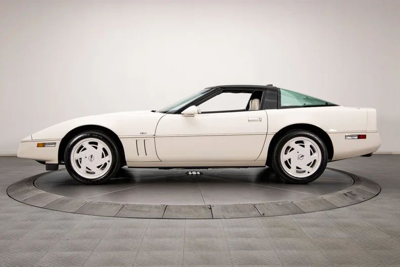 In the first design iteration of the C4 Corvette (including this 1988 Anniversary Edition seen here), the Corvette was still in its original C4 body styling form, first introduced in 1984. While the car already had the sharp, wedge-shaped look that defined the C4, there were several exterior styling elements specific to the initial design that would be re-imagined for the 1991 model year.  These elements included: A smooth and fairly plain front nose, with a flat, body-colored front bumper and narrow black rub strip that ran across the front and continued down the body sides. The turn signals were small rectangular units integrated low in the bumper. The sides were defined by a sharp body crease and the black rub strip that bisected the car all the way around. Side gills behind the front wheels were simple horizontal slats—thin, parallel louvers cut into the panel. The back end retained the flat panel with four round taillights set in a recessed, body-colored panel. The rear bumper was fairly vertical and squared off. Overall, the character of the first design iteration was angular, sharp-edged, and very much an '80s-era high-tech wedge design.  (Image courtesy of RK Motors.)