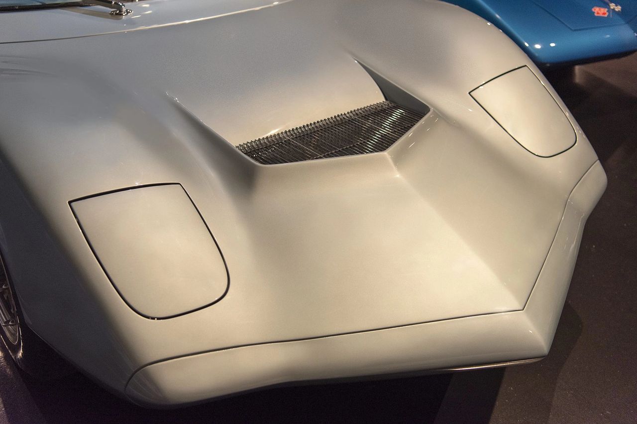 Up front, the XP-819 wears a deep, functional duct that pulls high-pressure air through the nose and then ejects it up and over the body, helping both cooling and front-end stability. It’s not just a styling flourish; this was GM Engineering and Styling teaming up to bleed off lift and manage airflow on a car that was already fighting the balance challenges of a rear-engine layout. Decades later, the C7 Corvette would revisit that same playbook with its prominent hood extractor, using a similar “front-in, top-out” strategy to cool the radiator and keep the nose planted at speed. In many ways, the XP-819’s scoop is an early chapter in the aero story that finally came of age on the seventh-generation Corvette. (Image courtesy of Joe Kolecki/Kolecki Photography) Up front, the XP-819 wears a deep, functional duct that pulls high-pressure air through the nose and then ejects it up and over the body, helping both cooling and front-end stability. It’s not just a styling flourish; this was GM Engineering and Styling teaming up to bleed off lift and manage airflow on a car that was already fighting the balance challenges of a rear-engine layout. Decades later, the C7 Corvette would revisit that same playbook with its prominent hood extractor, using a similar “front-in, top-out” strategy to cool the radiator and keep the nose planted at speed. In many ways, the XP-819’s scoop is an early chapter in the aero story that finally came of age on the seventh-generation Corvette. (Image courtesy of Joe Kolecki/Kolecki Photography)