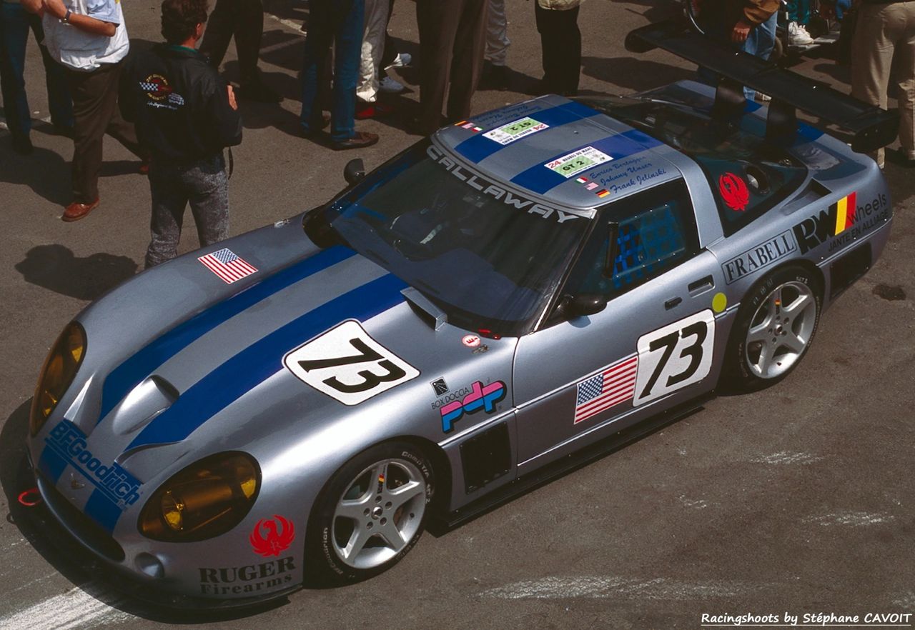 Scrutineering tells the truth on #73. Roof stickers and driver flags march across the panel, CALLAWAY shouts from the visor, and the silver body with twin blue stripes looks purposeful, not pretty. Yellow headlamp film, a deep center duct, and a NACA scoop feeding the front brakes telegraph the brief. Big side extractors and a tall, single-plane wing square the C4’s shoulders, while five-spoke Speedlines tuck neatly under the arches. The sponsor set—BFGoodrich, Ruger, Frabell, RW Wheels—reads period-correct, but it’s the small stuff that sells it: tow eye peeking from the splitter, quick-release pins, hand-cut numbers. This is a car built for the long night, not the lawn.