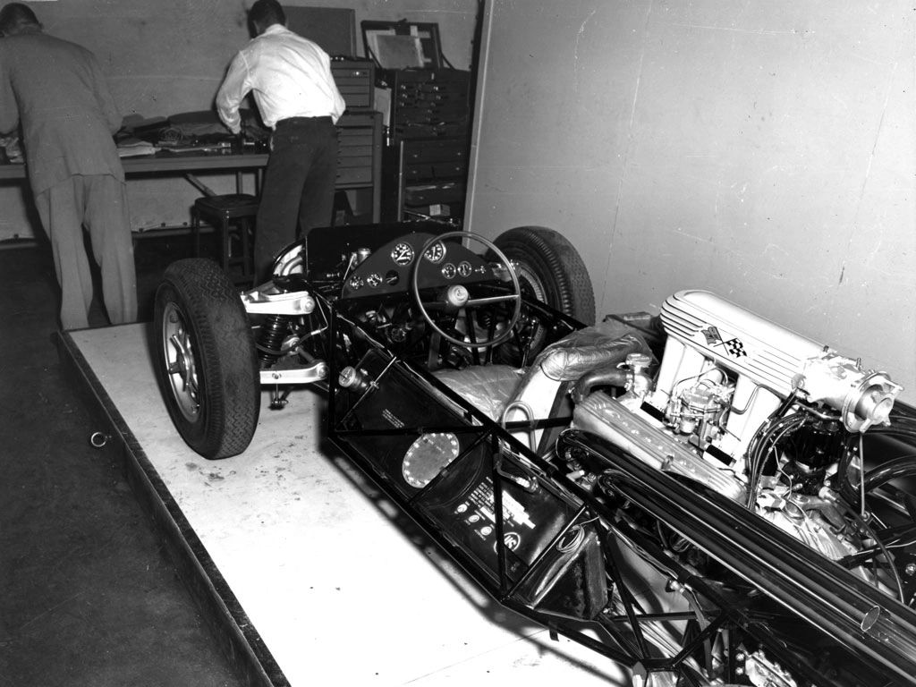On a jig table in Chevrolet Engineering, Duntov’s group built CERV I’s chassis like an aircraft truss—thin-wall tubing, tight triangulation, and welded bulkheads to carry the mid-mounted small-block. Pickup points were drilled, shimmed, and slotted so the team could sweep camber gain, caster, roll centers, and anti-effects between runs. Independent suspension at both ends, quick 12:1 steering (2.3 turns lock-to-lock), and forward-mounted, low-compliance linkages were chosen to kill slop and kickback, not the feedback. Lightweight hardware—magnesium wheels and liberal use of aluminum—trimmed unsprung mass so the steering “spoke” with clarity. What you see in this photo is the purpose-built lab GM wanted: open cockpit, exposed tanks and plumbing, everything accessible for rapid changeovers—an engineer’s testbed designed to turn geometry experiments into hard data and, ultimately, better Corvettes. (Image courtesy of GM Media LLC)