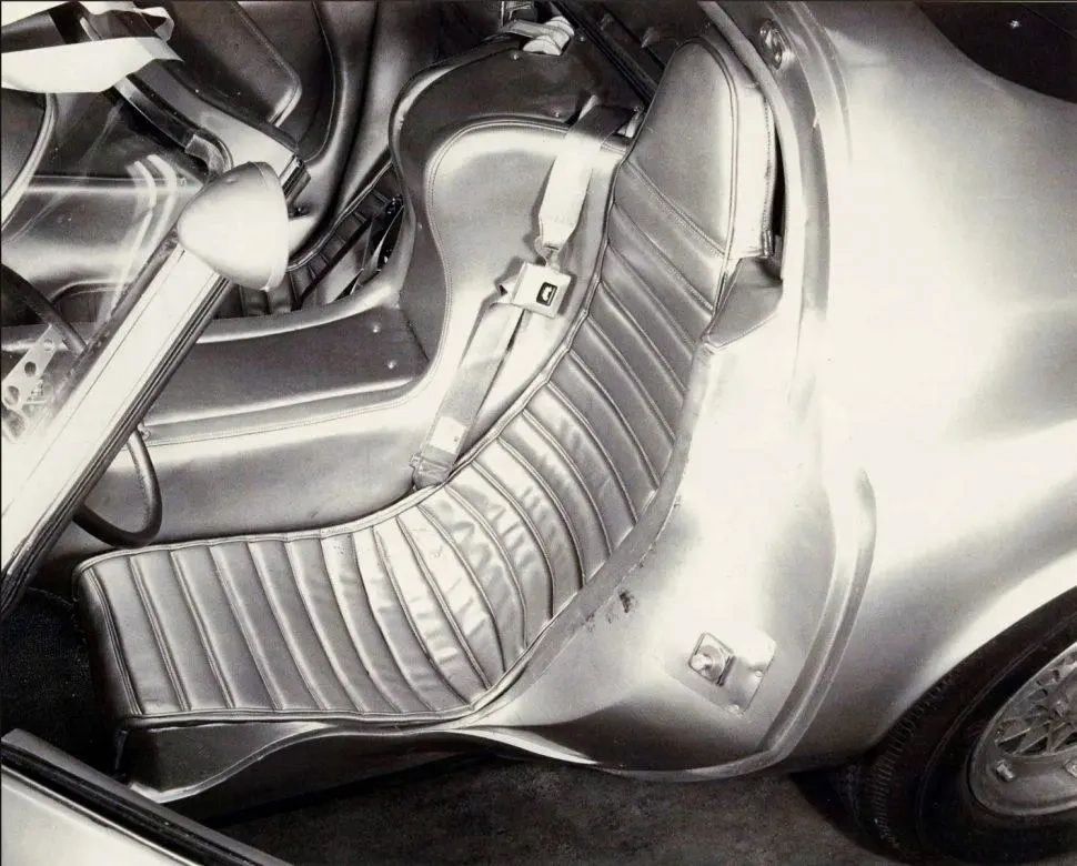 The XP-819’s seat was molded directly into the chassis tub, creating a fixed, laid-back driving position that locked the driver into the car rather than simply sitting on top of it. Instead of adjusting the seat, the rest of the cockpit—including the pedal box—was designed to move to the driver, an experiment in ergonomics that was decades ahead of its time. The XP-819’s seat was molded directly into the chassis tub, creating a fixed, laid-back driving position that locked the driver into the car rather than simply sitting on top of it. Instead of adjusting the seat, the rest of the cockpit—including the pedal box—was designed to move to the driver, an experiment in ergonomics that was decades ahead of its time.