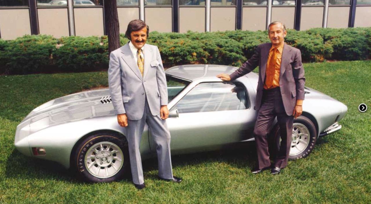 The image shows the completed XP-987 GT/2-Rotor Corvette body at Pininfarina, still in its bare silver finish before receiving its final show-car paint. Standing beside it are key GM design leaders Jim Juif and Clare “Mac” MacKichan, who helped champion the mid-engine, rotary-powered Corvette concept inside GM’s Experimental Studio. Seeing the sleek Italian-crafted bodywork mounted on its shortened Porsche 914 chassis gave GM management a tangible preview of how radical—and how refined—this new direction for Corvette could be. In many ways, moments like this courtyard photo were as important as any design sketch or clay model, turning an internal design study into a fully realized concept that GM could confidently send onto the world’s auto-show stages. The image shows the completed XP-987 GT/2-Rotor Corvette body at Pininfarina, still in its bare silver finish before receiving its final show-car paint. Standing beside it are key GM design leaders Jim Juif and Clare “Mac” MacKichan, who helped champion the mid-engine, rotary-powered Corvette concept inside GM’s Experimental Studio. Seeing the sleek Italian-crafted bodywork mounted on its shortened Porsche 914 chassis gave GM management a tangible preview of how radical—and how refined—this new direction for Corvette could be. In many ways, moments like this courtyard photo were as important as any design sketch or clay model, turning an internal design study into a fully realized concept that GM could confidently send onto the world’s auto-show stages.