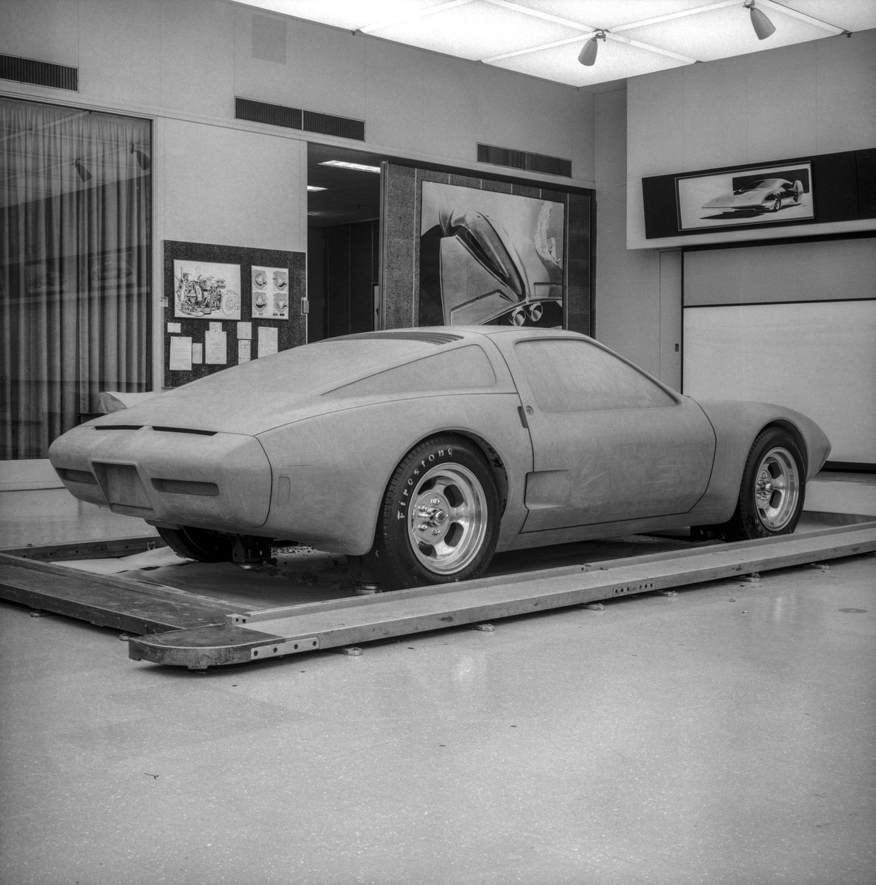 This black-and-white studio shot captures the XP-987 GT in one of its most critical stages of development—a full-size clay model sitting on the surface plate inside GM Design. With its broad haunches, short overhangs, and long, tapering rear deck, the car already communicates the purposeful stance of a true mid-engine Corvette, even before a single panel is stamped in steel or fiberglass. The taped-in glass lines, roughed-in scoops, and early bumper forms show designers still fine-tuning airflow, engine-cooling needs, and crash requirements. Period wheel-and-tire mockups give the model real-world proportions, helping the team judge how the XP-987 GT would sit on the road. Scenes like this are where radical ideas stopped being sketches on the wall and started becoming three-dimensional reality. (Image courtesy of GM Media LLC) This black-and-white studio shot captures the XP-987 GT in one of its most critical stages of development—a full-size clay model sitting on the surface plate inside GM Design. With its broad haunches, short overhangs, and long, tapering rear deck, the car already communicates the purposeful stance of a true mid-engine Corvette, even before a single panel is stamped in steel or fiberglass. The taped-in glass lines, roughed-in scoops, and early bumper forms show designers still fine-tuning airflow, engine-cooling needs, and crash requirements. Period wheel-and-tire mockups give the model real-world proportions, helping the team judge how the XP-987 GT would sit on the road. Scenes like this are where radical ideas stopped being sketches on the wall and started becoming three-dimensional reality. (Image courtesy of GM Media LLC)