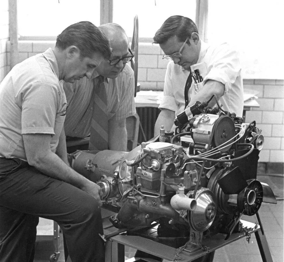 Three engineers crowd around an early prototype of GM’s rotary combustion engine, studying every fitting and fastener as it sits on a test stand. This is where the Wankel dream became real work—fuel lines routed, ignition mocked up, housings checked and rechecked before the engine ever met a chassis. In rooms like this, far from auto-show spotlights, GM’s team chased Ed Cole’s vision of a compact, high-revving rotary that could power the next-generation Corvette. Even if the program ultimately fell short, moments like this capture the quiet intensity behind the XP-987 GT story. Three engineers crowd around an early prototype of GM’s rotary combustion engine, studying every fitting and fastener as it sits on a test stand. This is where the Wankel dream became real work—fuel lines routed, ignition mocked up, housings checked and rechecked before the engine ever met a chassis. In rooms like this, far from auto-show spotlights, GM’s team chased Ed Cole’s vision of a compact, high-revving rotary that could power the next-generation Corvette. Even if the program ultimately fell short, moments like this capture the quiet intensity behind the XP-987 GT story.