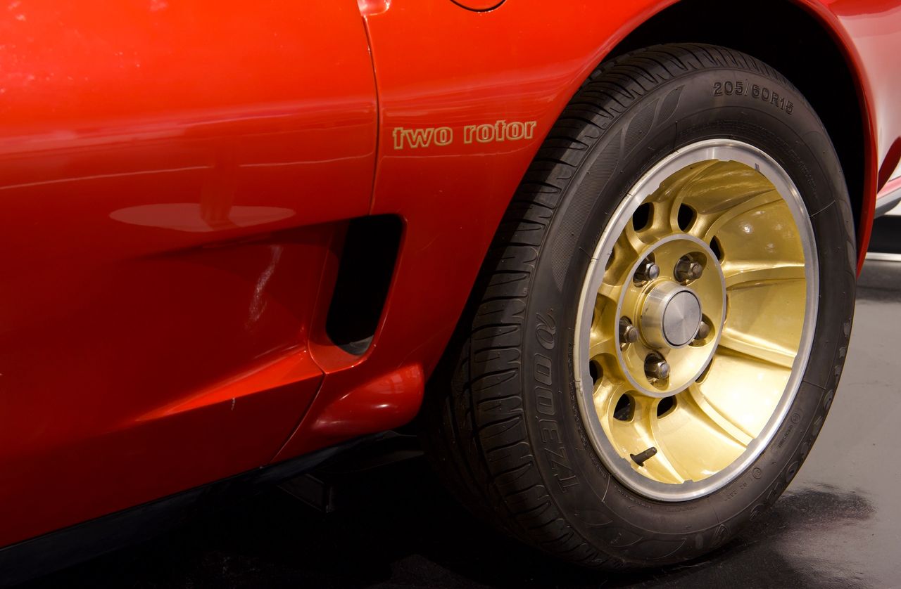 Up close, the XP-987 GT’s gold-finished turbine-style wheels instantly signal that this is no ordinary mid-engine prototype—they give the car a bold, almost competition-ready stance that fits its experimental mission. Just ahead of the rear wheel, the subtle “two rotor” script hints at the unconventional powerplant originally planned for the car, proudly calling out the Wankel engine configuration. Elsewhere on the body (not seen here), “Corvette Two-Rotor” decals were added to further “Americanize” the Pininfarina-built shape and clearly link this Italian-crafted body back to Chevrolet’s flagship sports car. Together, the wheels and graphics helped transform what began as a Porsche-based test bed into something that unmistakably read as a futuristic Corvette—at least to the executives and show-goers Chevy most wanted to impress. (Image courtesy of Joe Kolecki/Kolecki Photography LLC) Up close, the XP-987 GT’s gold-finished turbine-style wheels instantly signal that this is no ordinary mid-engine prototype—they give the car a bold, almost competition-ready stance that fits its experimental mission. Just ahead of the rear wheel, the subtle “two rotor” script hints at the unconventional powerplant originally planned for the car, proudly calling out the Wankel engine configuration. Elsewhere on the body (not seen here), “Corvette Two-Rotor” decals were added to further “Americanize” the Pininfarina-built shape and clearly link this Italian-crafted body back to Chevrolet’s flagship sports car. Together, the wheels and graphics helped transform what began as a Porsche-based test bed into something that unmistakably read as a futuristic Corvette—at least to the executives and show-goers Chevy most wanted to impress. (Image courtesy of Joe Kolecki/Kolecki Photography LLC)