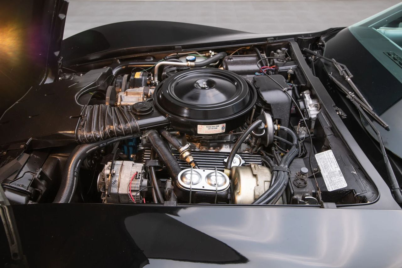 The L82 350 was the hot small-block in 1978—rated at 220 hp thanks to a higher-lift cam, 8.9:1 compression, aluminum intake, and a Rochester Quadrajet 4-bbl under that dual-snorkel air cleaner. Finned aluminum valve covers and HEI ignition marked it out underhood, while the close-ratio 4-speed made the most of its mid-range. In period testing, an L82/4-speed Corvette could run 0–60 in the mid-sixes and the quarter in the mid-15s—serious pace for the emissions era. More than a decal special, the L82 gave the ’78 Pace Car real substance to match the spectacle. (Image courtesy of RK Motors) The L82 350 was the hot small-block in 1978—rated at 220 hp thanks to a higher-lift cam, 8.9:1 compression, aluminum intake, and a Rochester Quadrajet 4-bbl under that dual-snorkel air cleaner. Finned aluminum valve covers and HEI ignition marked it out underhood, while the close-ratio 4-speed made the most of its mid-range. In period testing, an L82/4-speed Corvette could run 0–60 in the mid-sixes and the quarter in the mid-15s—serious pace for the emissions era. More than a decal special, the L82 gave the ’78 Pace Car real substance to match the spectacle. (Image courtesy of RK Motors)