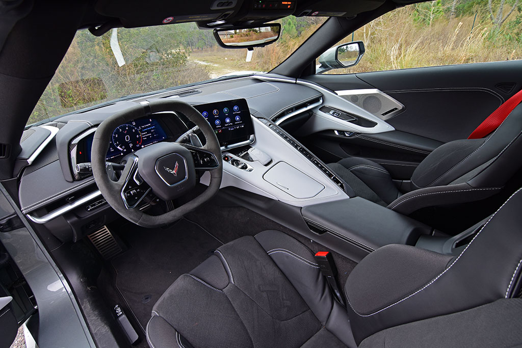 Interior of a 2022 Corvette Stingray equipped with the 2LT trim, showing the driver-focused cockpit, digital instrument cluster, central touchscreen, head-up-display controls, two-tone dashboard, and black sport seats.