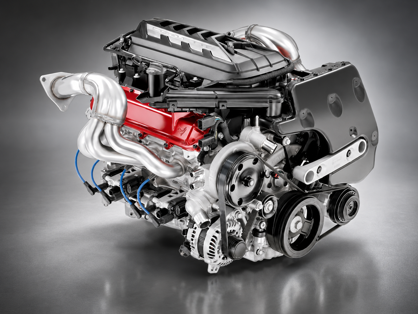 Studio image of the 2022 Corvette Stingray’s 6.2-liter LT2 V8 engine, showing its red valve covers, intake assembly, exhaust headers, accessory pulleys, and exposed mechanical components.