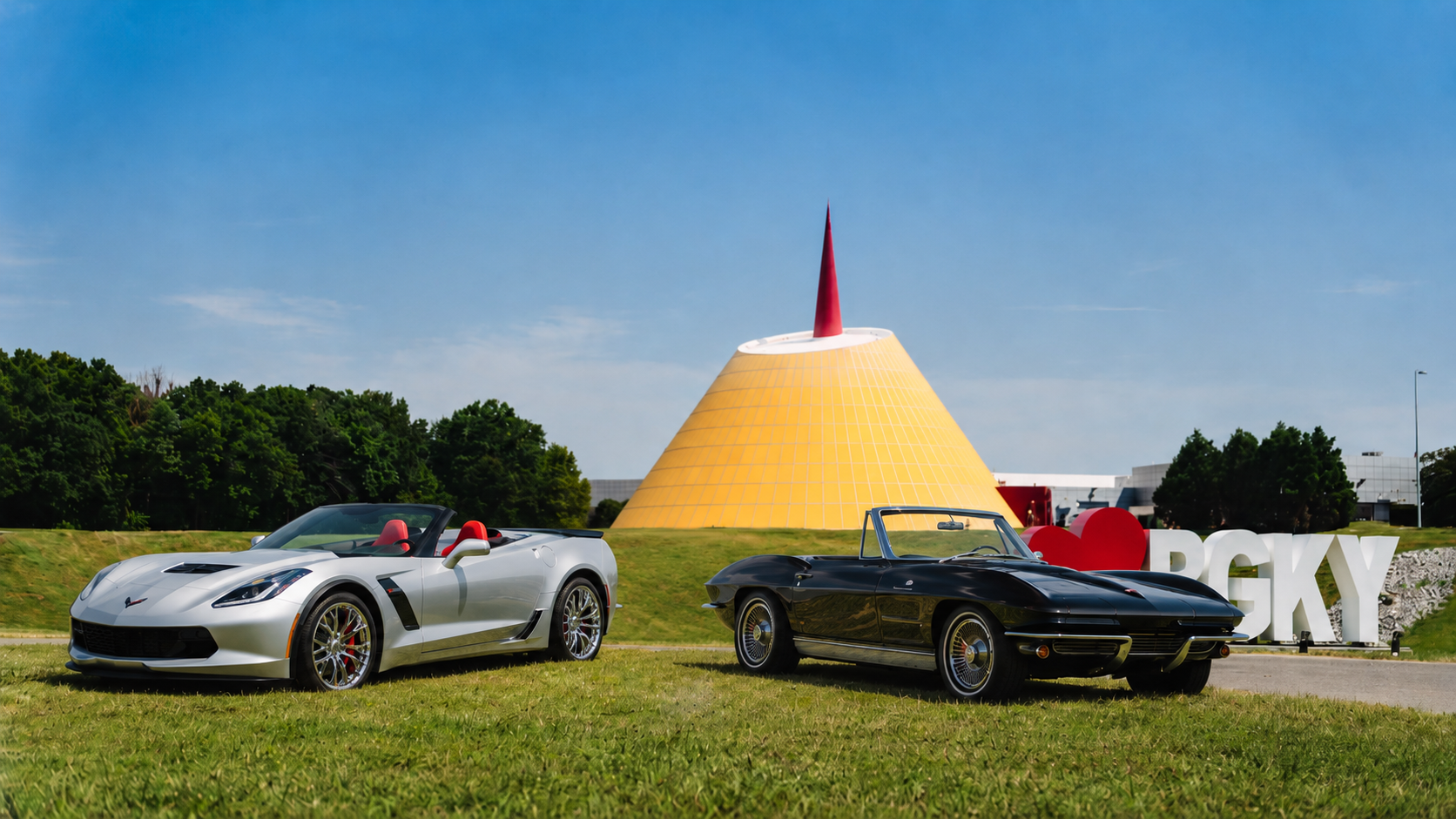 A silver 2015 Chevrolet Corvette Z06 Convertible and a black 1963 Corvette Z06 Convertible displayed together on the grounds of the National Corvette Museum in Bowling Green, Kentucky.