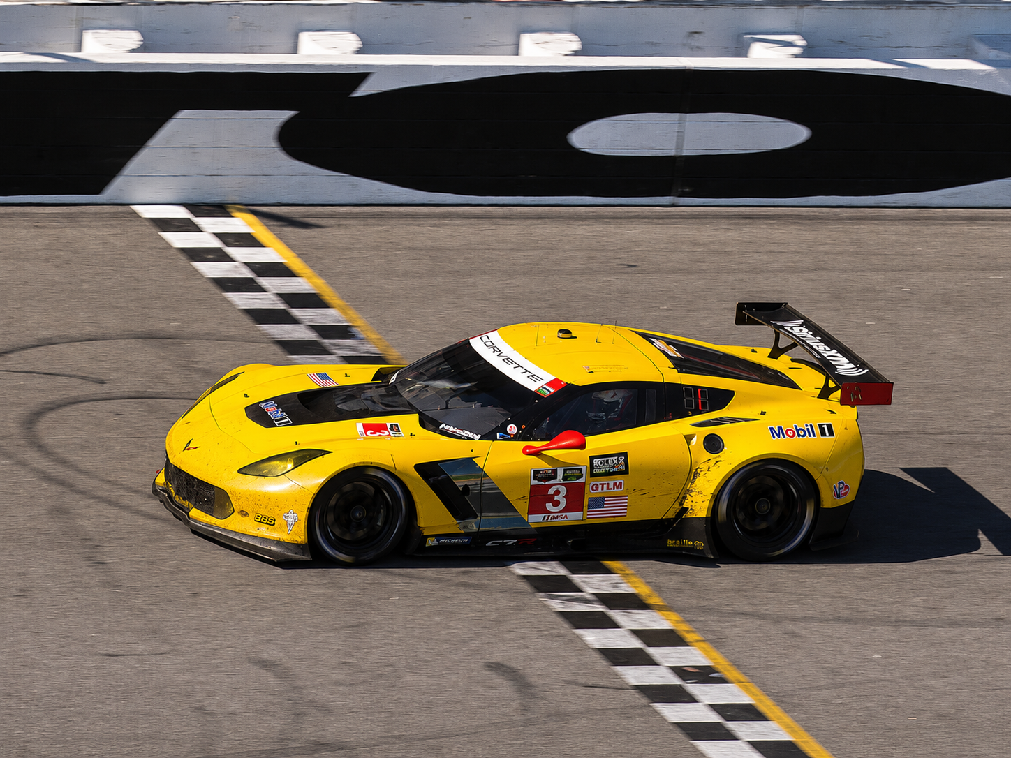 Yellow No. 3 Corvette C7.R crossing the start-finish line at Daytona International Speedway during the 2015 Rolex 24, where Antonio García, Jan Magnussen and Ryan Briscoe captured the GT Le Mans class victory.