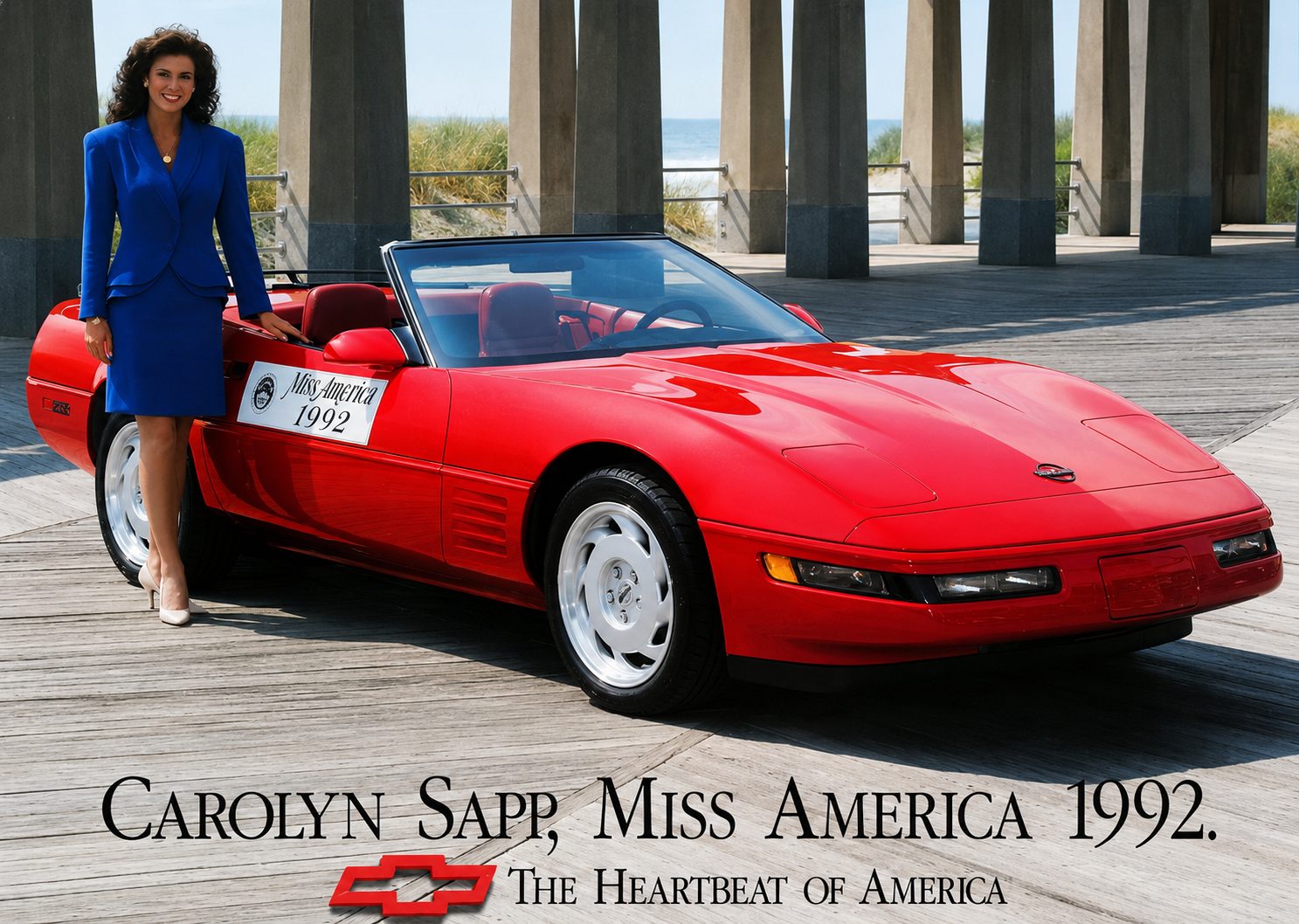 Miss America 1992 Carolyn Sapp of Hawaii poses beside a red Chevrolet Corvette convertible on a seaside boardwalk in a Chevrolet “Heartbeat of America” promotional photograph.