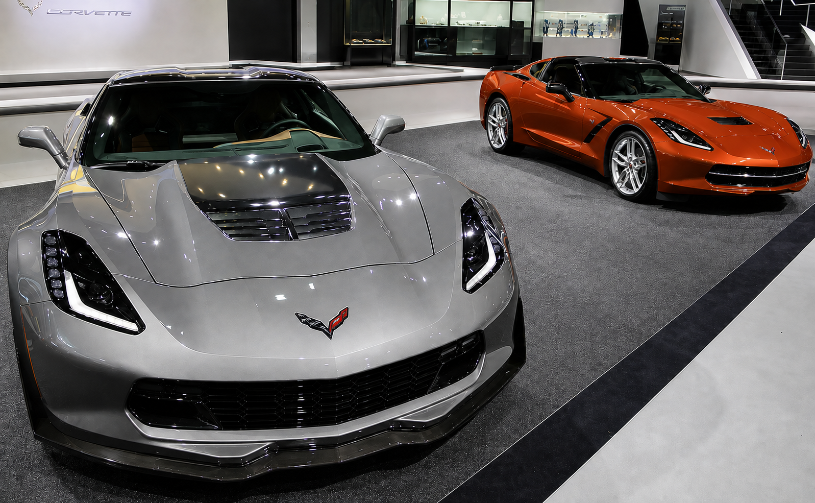 Shark Gray Metallic and Daytona Sunrise Orange Metallic 2015 Chevrolet Corvettes displayed together, highlighting the two new exterior paint colors introduced for the 2015 model year.