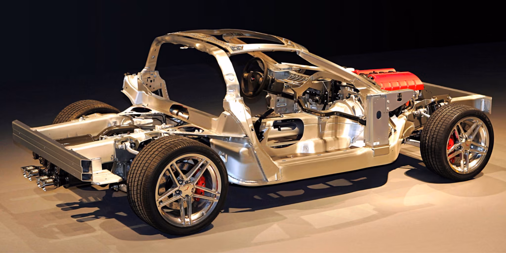 Exposed aluminum chassis and structural framework of the 2006 Chevrolet Corvette Z06, revealing its hydroformed aluminum frame rails, fixed roof support structure, magnesium engine cradle, front-mounted LS7 V8, suspension components, wheels, and high-performance braking system.