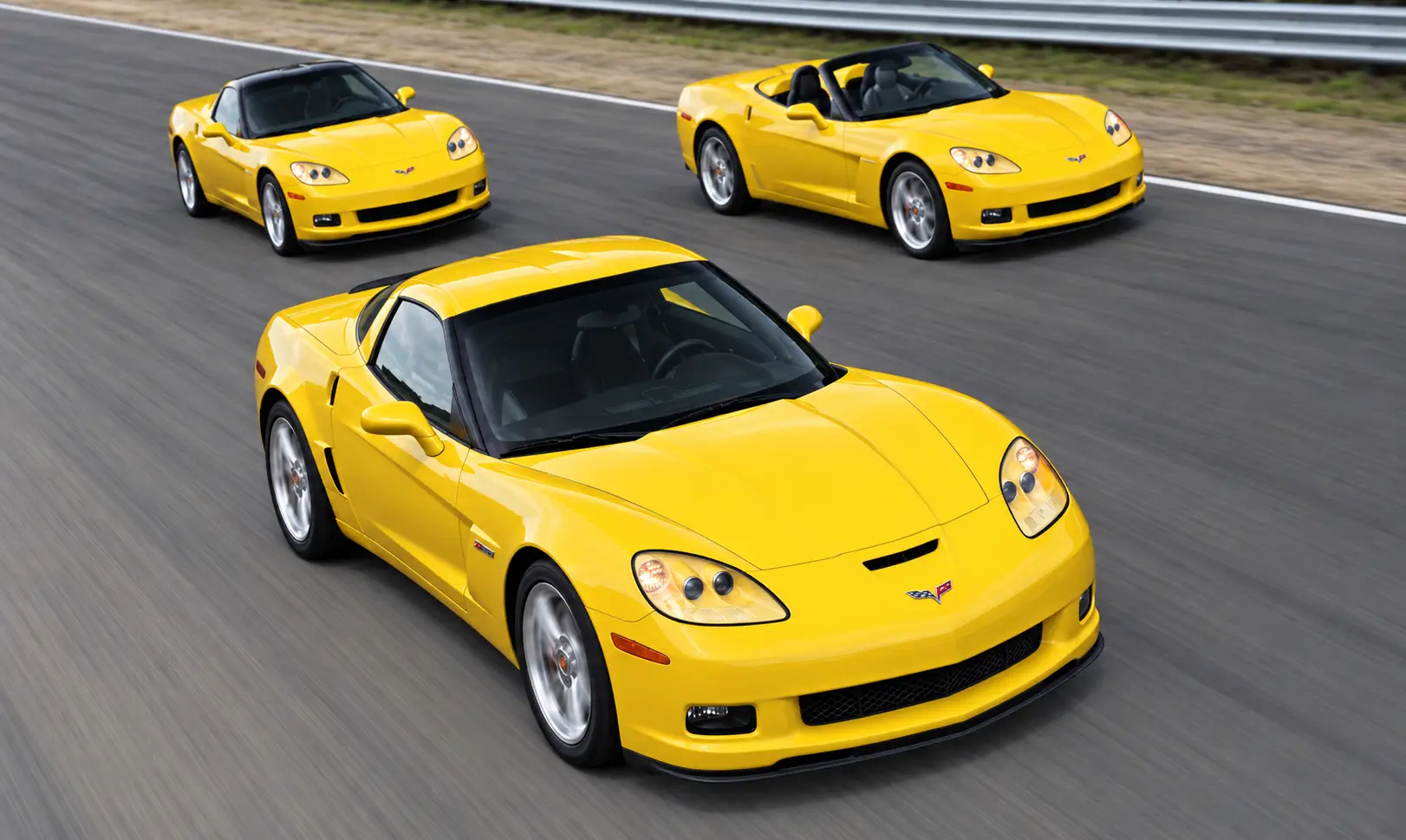 Three yellow 2006 Chevrolet Corvettes—a Z06 in the foreground, a standard coupe at upper left, and a convertible at upper right—driving together on a racetrack, illustrating the performance and versatility of the C6 lineup.