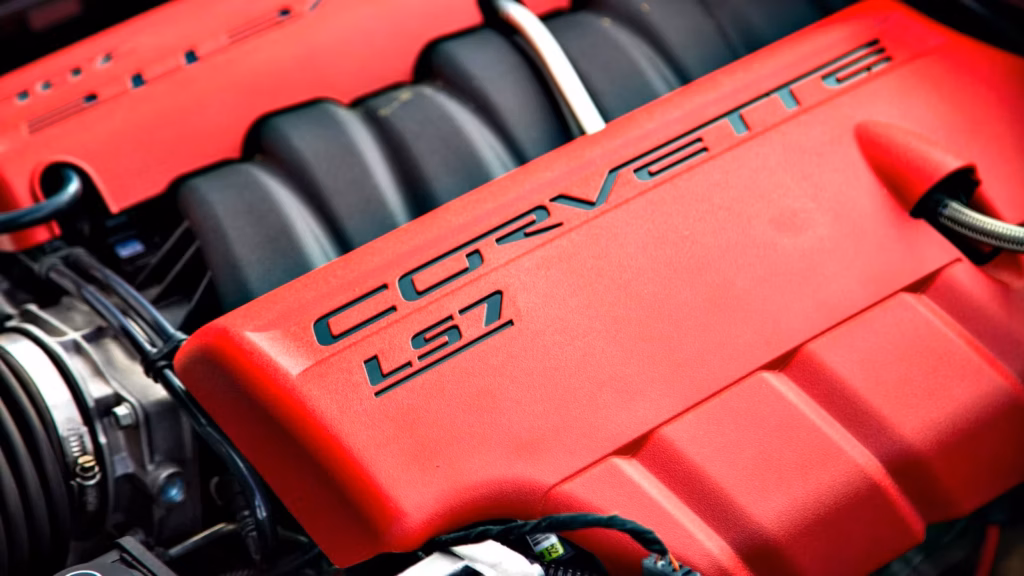Close-up photograph of the 2006 Chevrolet Corvette Z06's LS7 7.0-liter V8 engine, showcasing its distinctive bright red engine covers with black CORVETTE LS7 lettering and the black intake manifold positioned between the cylinder banks.